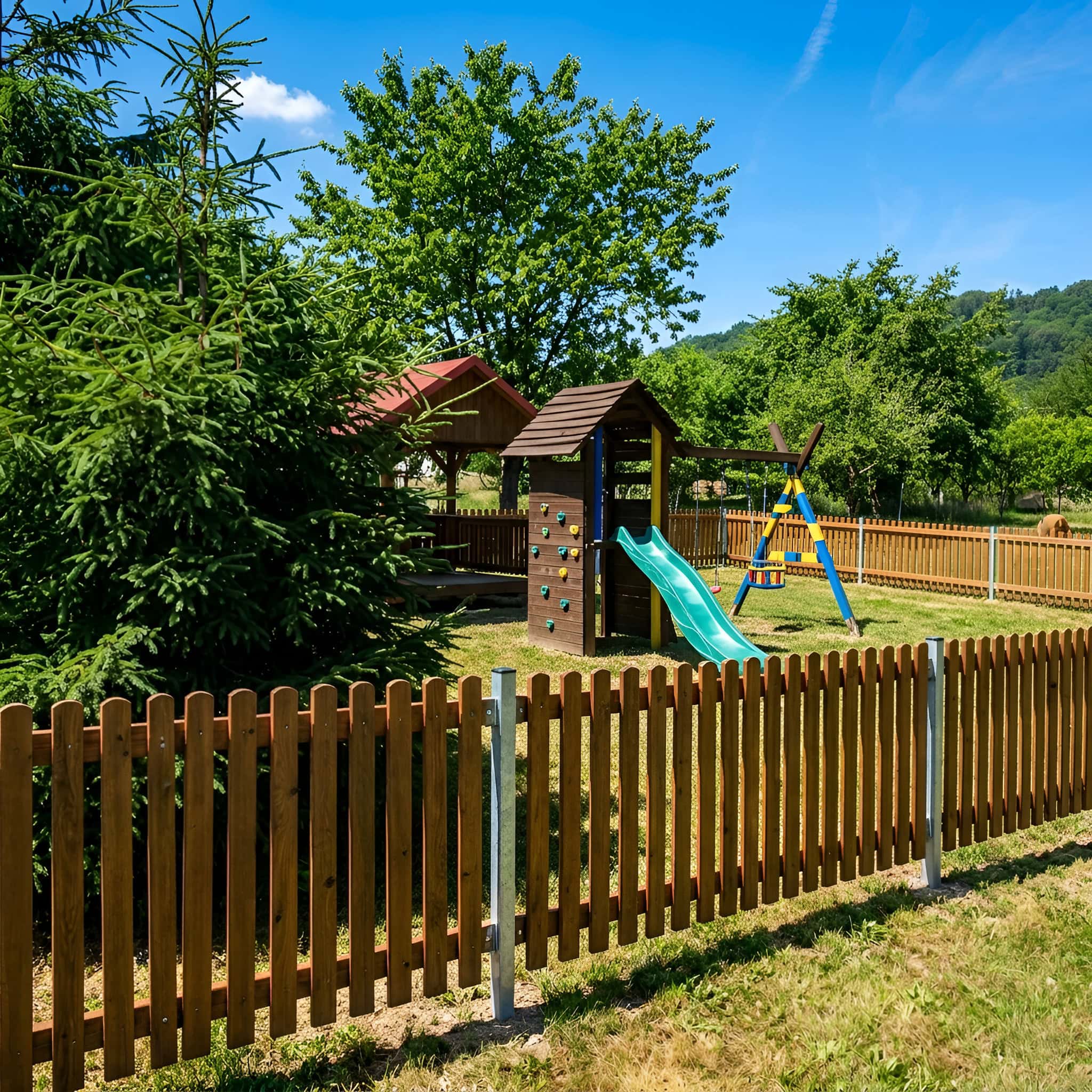Dřevěný plot ze zaoblených latí v zahradě u dětského hřiště